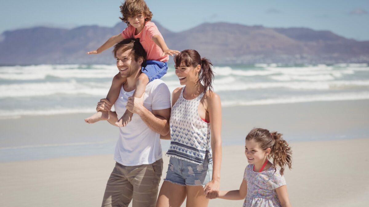 Um casal com dois filhos na praia durante uma viagem em família