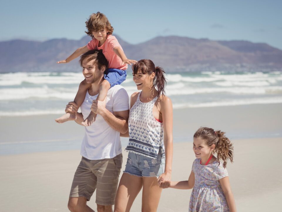Um casal com dois filhos na praia durante uma viagem em família